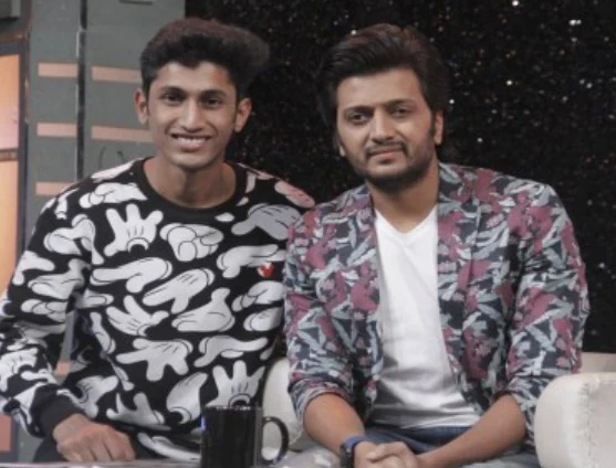 Two artists seated together and smiling for a photo at an event.