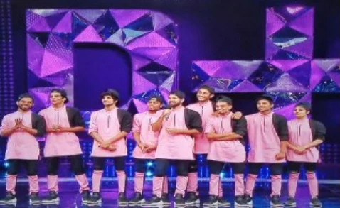 The crew in pink jackets gathered on a television stage for a ceremony.