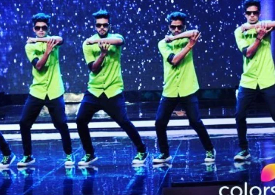 Crew in green shirts performing together on a televised dance stage.
