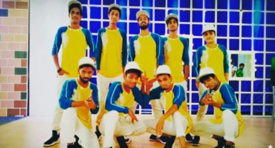 Dance crew posing together in coordinated yellow and blue outfits.